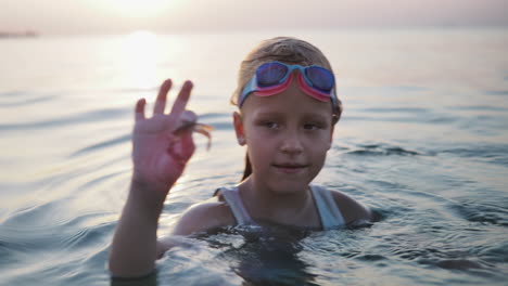 girl playing with crab in the ocean at sunset