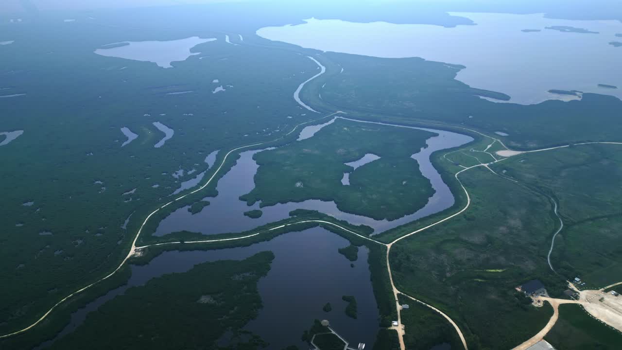 Drone orbits high above wetlands, revealing roads, paths, and distant ponds