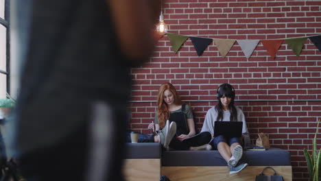 group of diverse business students studying using laptop computer working on project in relaxed office workplace listening to music wearing headphones