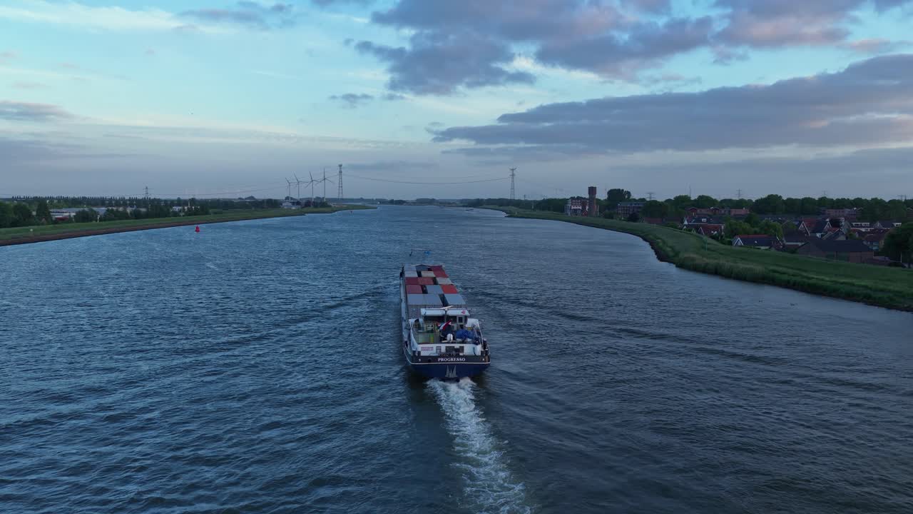 Following aerial movement behind the Progresso Dordrecht cargo ship cruising alone on the wide river channel, Zuid-Holland, Netherlands