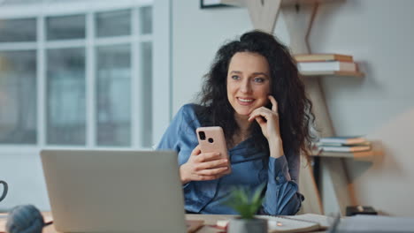 Smiling executive browsing cellphone at workplace. Relaxed businesswoman texting