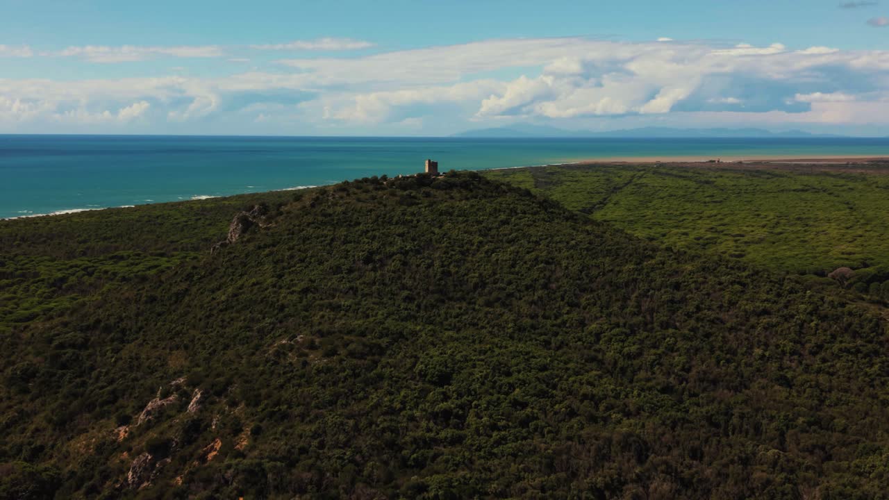 Old stone watchtower overlooks Maremma wild forest landscape and the blue sea of southern Tuscany
