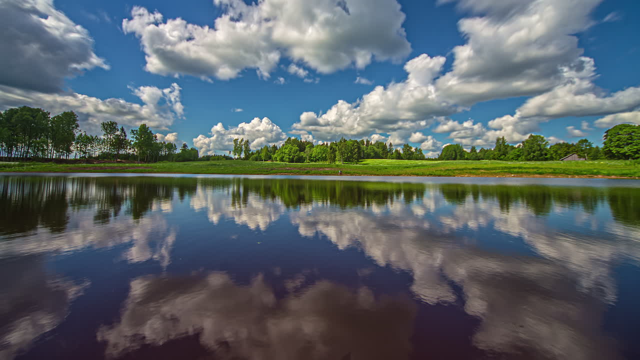disparo de lapso de tiempo del movimiento de las nubes sobre un lago a lo largo de un paisaje rural con vegetación verde durante todo el día