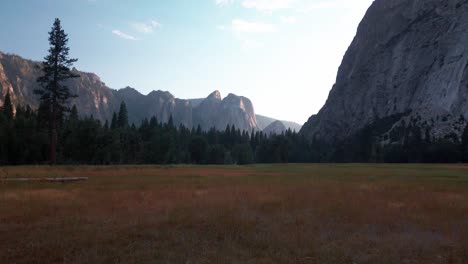 Tilting-up-shot-from-golden-meadow-to-silhouetted-granite-monoliths-at-low-light