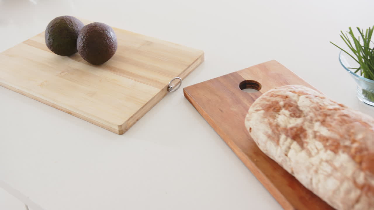 Preparing fresh ingredients, avocados and bread on cutting boards in kitchen, at home