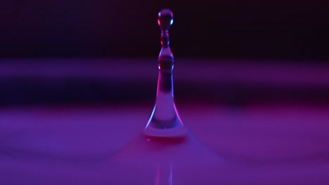 Gota-De-Agua-Que-Cae-En-El-Agua,-Vista-Macro-Cercana,-Cámara-De-Cine-En-Cámara-Lenta,-1000-Fps,-Fondo-Morado