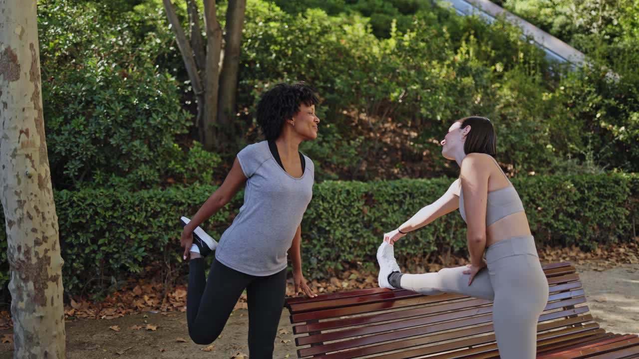 Due giovani donne che fanno stretching insieme in un parco soleggiato