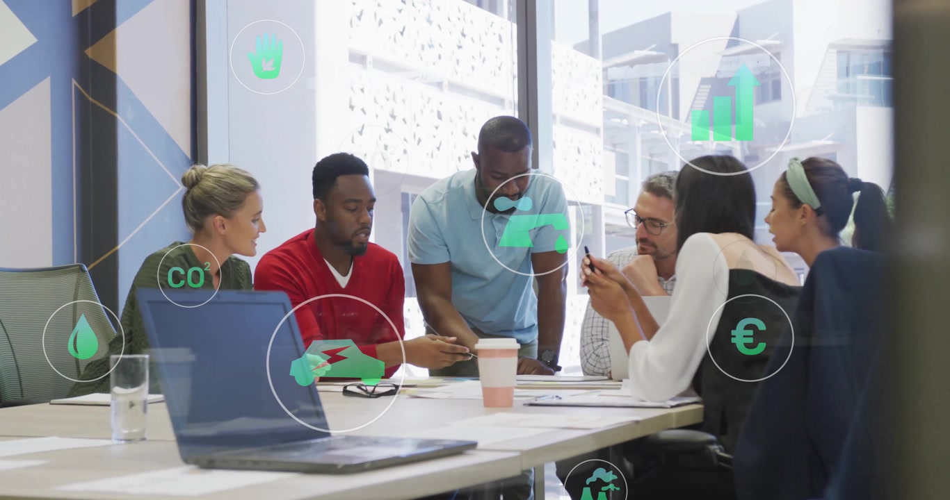 Diverse team collaborating at office with eco-friendly icons overlay animation