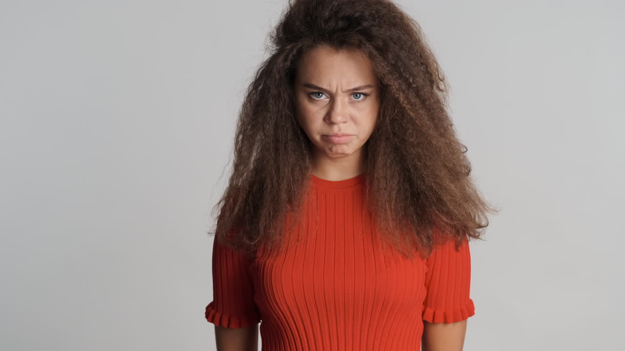 Angry Caucasian curly haired woman shouting to the camera.