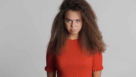 una mujer caucásica con el pelo rizado gritando a la cámara.