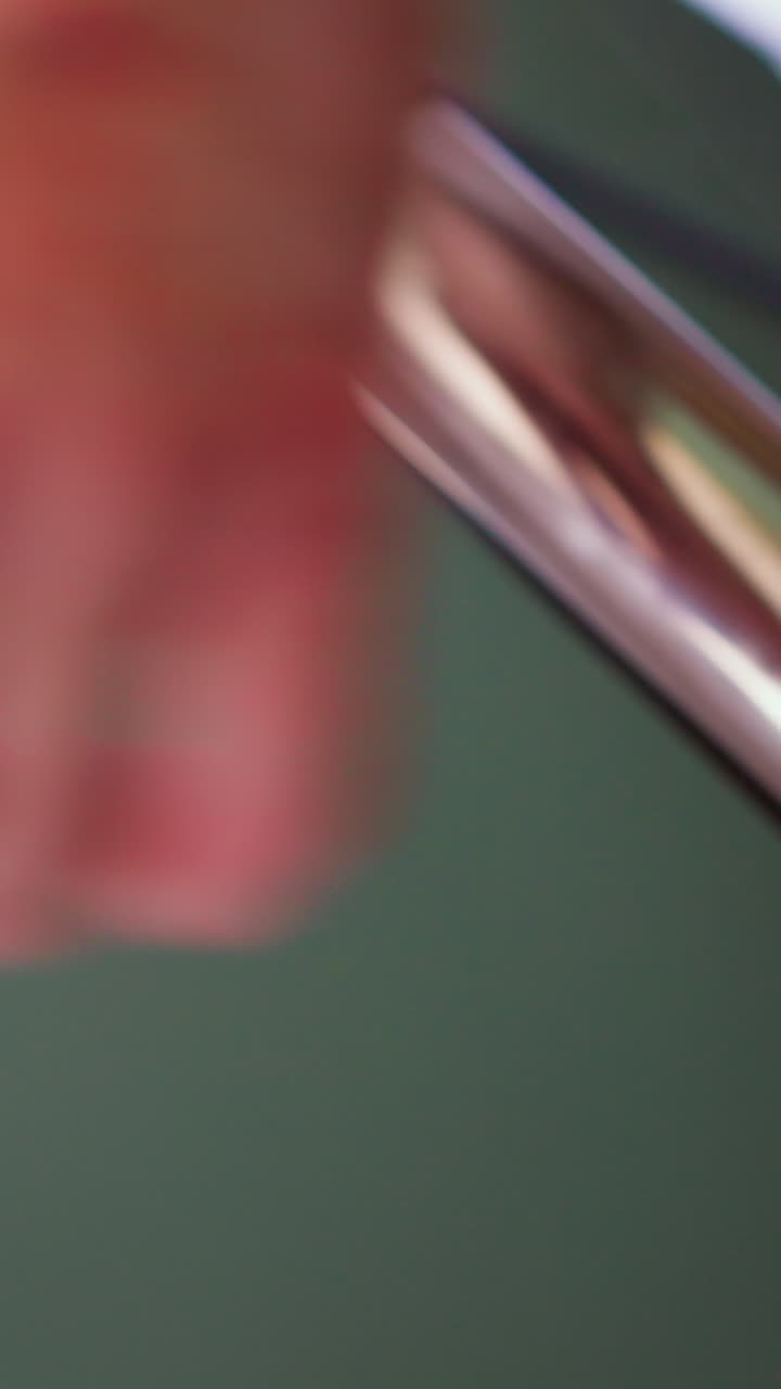 Hairdresser uses hot curling iron to make stylish lock to female client in contemporary professional beauty salon extreme close view slow motion