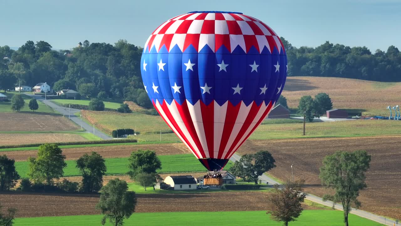 Drone che orbita attorno a una mongolfiera con la bandiera americana sopra i campi agricoli del Paese Amish, Pennsylvania, USA