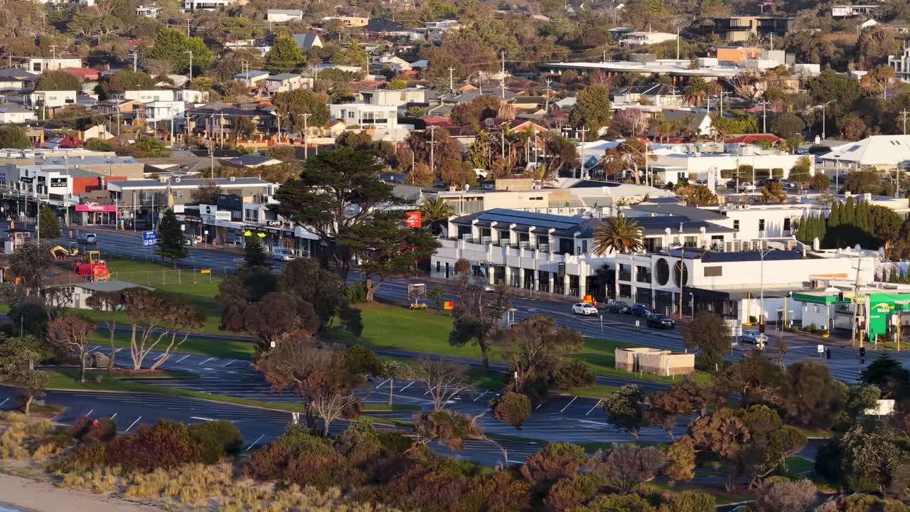 Drone camera smoothly pans above Rye’s main street, revealing shops, trees, and suburban landscape