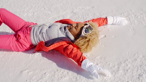 smiling woman in snowsuit laying on snow