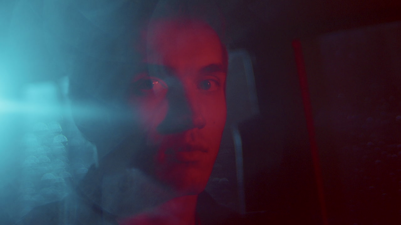 Portrait of Young Man in Car Illuminated by Red and Blue Lights at Night