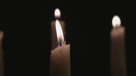 four white candles lit and a fast pan across them in slow motion