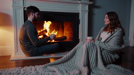una pareja relajándose junto a la chimenea.