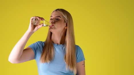 young woman drinking water from a glass bottle