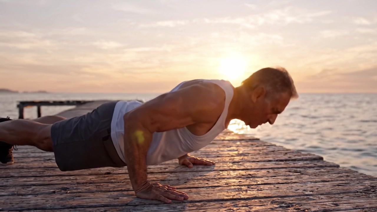 Un uomo in forma che fa flessioni su un molo panoramico al tramonto, abbracciando fitness e serenità in una splendida cornice naturale, mostrando forza e determinazione.