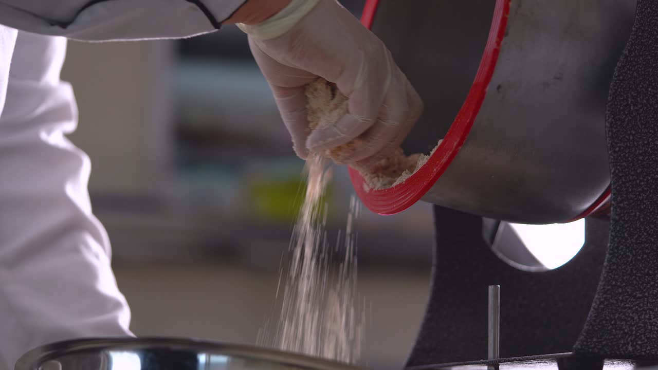 un chef de pastelería francés descarga almendras molidas de una máquina de molienda de grano