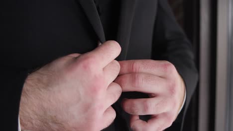 wedding groom using his hands to adjust his black suit during his wedding day