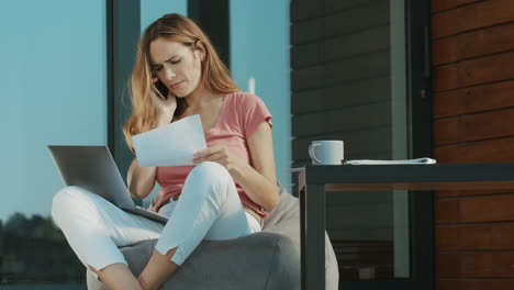 Angry-woman-talking-with-documents-on-terrace.-Upset-woman-speaking-mobile.