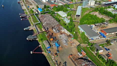 Aerial-drone-shot-flying-over-scrap-yard-with-pile-of-crushed-cars-in-Riga,-Latvia-on-a-sunny-day