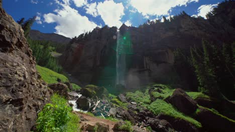 summer telluride box canyon bridal veil falls waterfall colorado landscape pan down slowly mist spray cliffside powerhouse hydroelectric power plant black bear pass board sunny blue sky clouds scenery