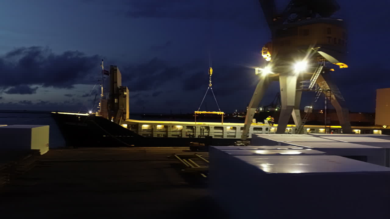 vuelo de drones alrededor de una grúa en el puerto cargando un barco por la noche