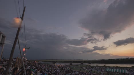 riverbank festival with fireworks at sunset