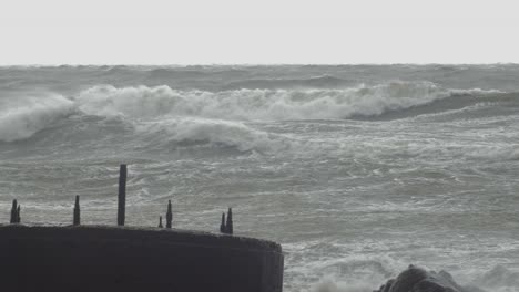 big waves hitting the abandoned concrete coast defense building ruins in stormy weather