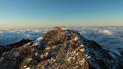 drone shot of people standing together watching the beautiful scenery on top of a mountain