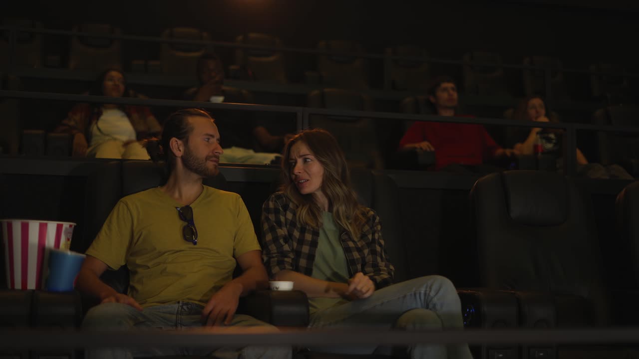 Una coppia ha un appuntamento al cinema, seduta e abbracciata.