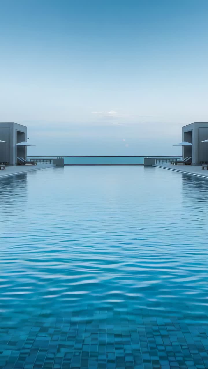 Vertikales Video: Unter leichter Brise kräuselnder Infinitypool, der den Blick an Cabanas vorbei zum Meer lenkt