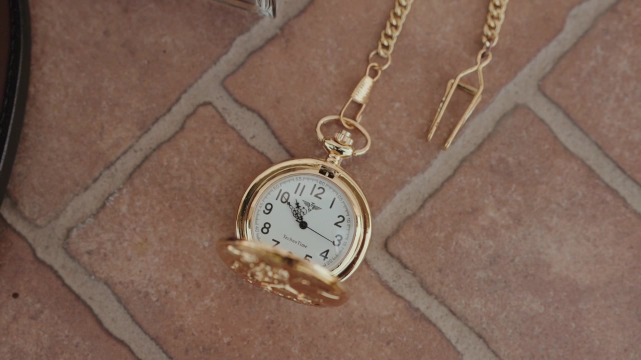 Antiguo reloj de bolsillo de oro con cadena, abierto mostrando la esfera blanca y números romanos