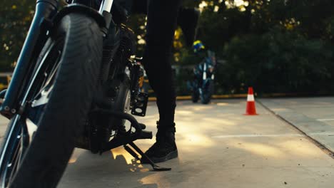 una chica motociclista profesional con ropa de protección especial y un casco se sienta en una motocicleta negra y comprueba su capacidad de servicio