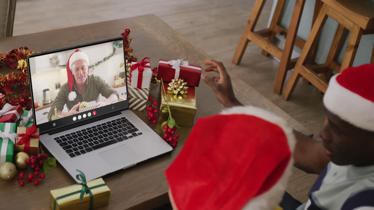 pareja diversa con sombreros de santa teniendo llamada de video portátil con hombre caucásico