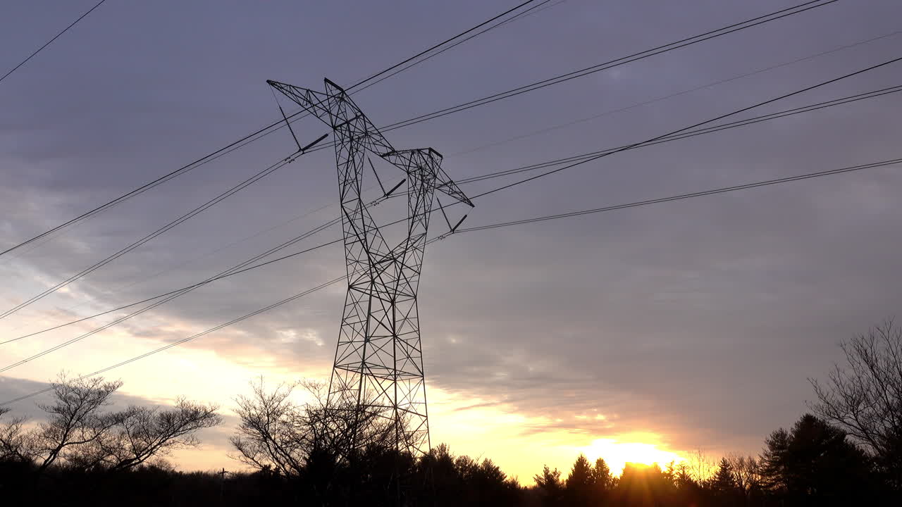Electrical tower against a cloudy sky at sunset