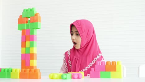 muslim girl plays the colorful jigsaw puzzles alone in room with white background