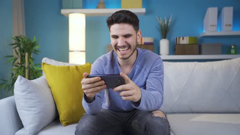 young man watching comedy movie on smartphone alone at home.