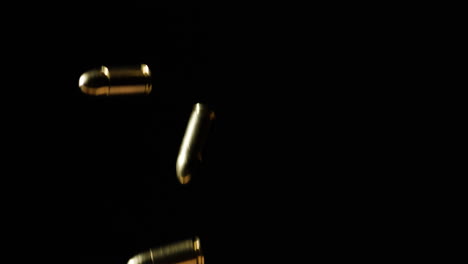 9mm-Parabellum-Firearms-Cartridge-Falling-In-Slow-Motion,-Isolated-In-Black-Backdrop