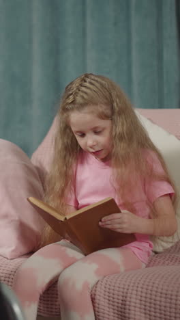 little boy sits on lap of mother in wheelchair while girl reading fairytale on couch. woman with disability watches children in living room closeup