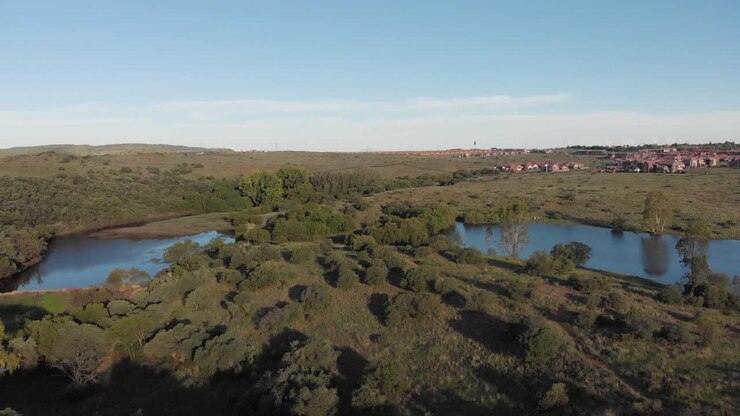 Ripresa aerea in controcampo di una diga in una valle verde con abitazioni sullo sfondo