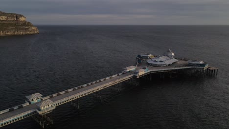 aerial drone flight heading out ove the pier in llandudno wales showing the great orme and coastline in the background