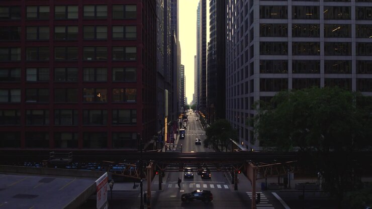 Veduta aerea con drone lungo un corridoio stradale del centro di Chicago con grattacieli, traffico in movimento, alberi e binari ferroviari sopraelevati della CTA che attraversano il primo piano