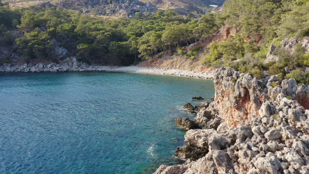 Flight along rocky cliff edge reveal idyllic Turkish azure blue water bay