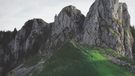 tilt-up camera movement showing a green meadow and mountain cliffs at sunset in the buila vanturarita carpathian mountains