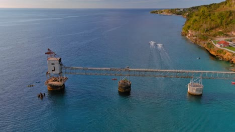 Zoom-De-Vista-De-Pájaro-En-Toma-De-Drones-De-Un-Muelle-De-Caña-De-Azúcar-Con-Jet-Ski-Navegando-En-El-Océano-Ubicado-En-Aguadilla,-Puerto-Rico