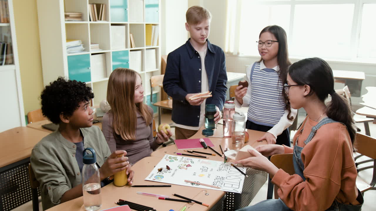 A group of diverse students eating snacks and socializing in a classroom