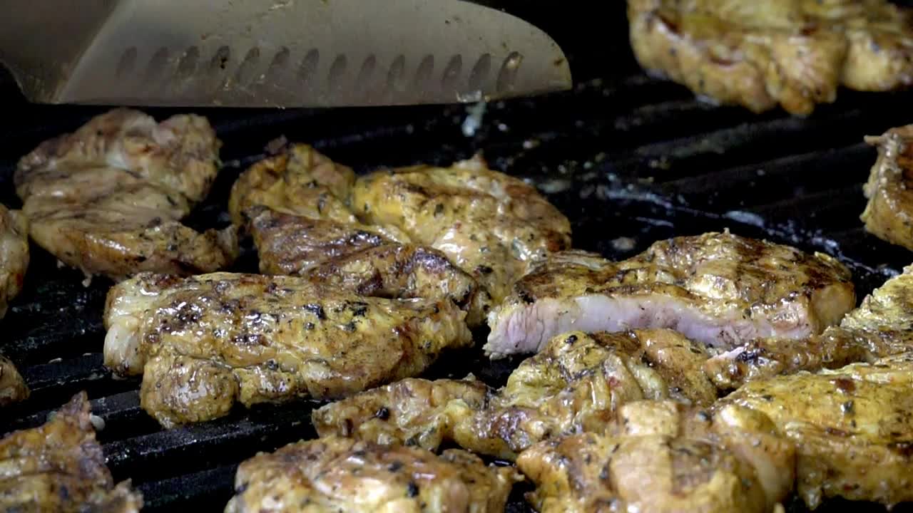 Cooking chicken on a bbq, cutting chicken pieces into smaller portions